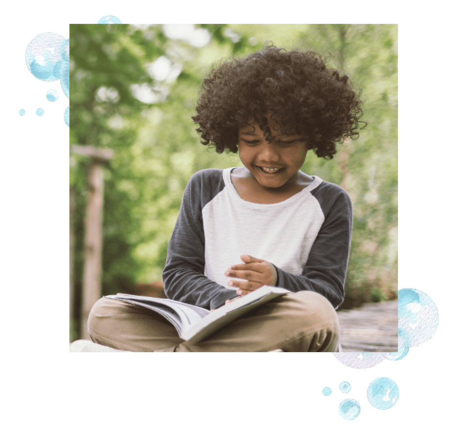 A boy reading a book and smiling.