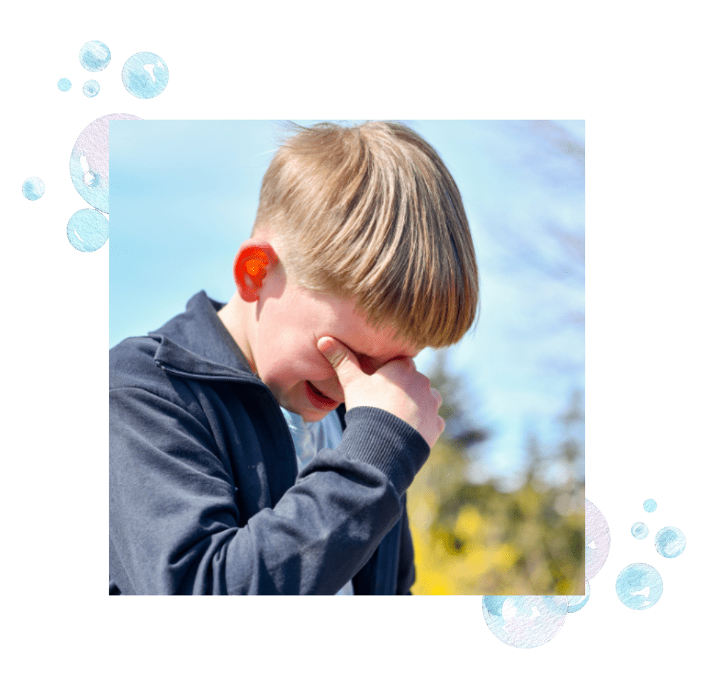 A boy crying with his hands in his face.