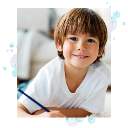 A cute, smiling boy using visual motor integration skills while he writes.